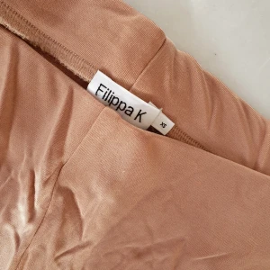  - OBS! Skrynkliga pga dåligt ihopvikta efter tvätt....   Filippa K byxor i ljus koppar/guld/brun färg.  Kan tänka mig att de passar bra till yoga, promenader, mys & gym. Aldrig använda!   Kan mötas upp i Huddinge, Älvsjö, Årsta, Globen & Västberga