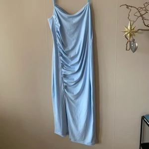 En oanvänd klänning ifrån ASOS strl 46 - Klänningen är ljusblå med sju detaljknappar och en slits, den är i storlek EU 46 och oanvänd. Frakt 4