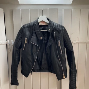 Moto jacket - Svart moto jacket skinnjacka från chiquelle. Använd ett fåtal gånger och är köpt i storlek xs men står 36 på lappen. Mc-inspirerad jacka i läderimitation med quiltade detaljer på axlar och i ärmslut. Två fickor med dragkedja framtill. Reglerbara bälten på sidorna.