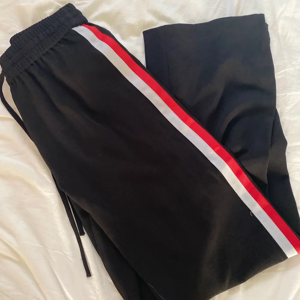 Coola svarta byxor som är jättesköna från Gina. De har vit röda sträck på båda sidorna av benen och snöre runt midjan så man kan justera storleken. . Jeans & Byxor.