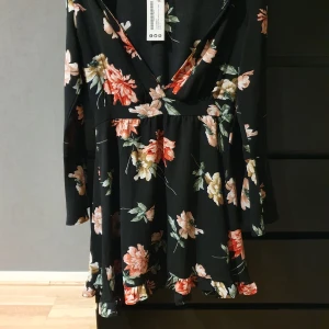 Blommig klänning  - Blommig klänning med volangarmar och urringning.