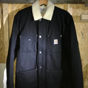Carhartt WIP - Carhartt WIP Fairmount coat i black rigid. Den är i storlek L och använd endast en gång, sedan hängt och tagit upp plats i garderoben. (Min killes) Den är i mycket bra skick 😊 kan skickas på posten eller mötas upp runt om Majorna Göteborg. Osäker på vad frakt ev kan hamna på så om du vill ha den postad får vi kika närmre på det. 😊🚚