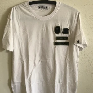 Bape x Undefeated Velcro Logo Tee - Bape / A Bathing Ape x Undefeated Velcro Logo T-Shirt  Size large, fits like a regular men’s medium. Great condition, no flaws or damage.  DM if you need exact size measurements.   Buyer pays for all shipping costs. All items sent with tracking number.   No swaps, no trades, no offers. 