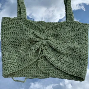 Virkad topp med knytning  - Egen virkad grön topp med knytning på framsidan. Materialet är stretchigt vilket gör att den båda passar för XS och S. Toppen är aldrig andvänd förutom på bild. Hör av dig om du har frågor eller funderingar💚