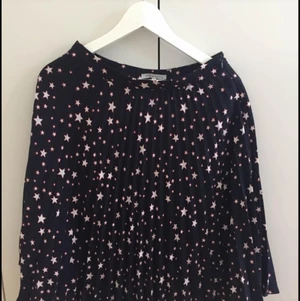 Kjol med stjärnor storlek 36 - Halvlång mörkblå kjol med vita stjärnor i storlek 36 från Mint & Berry. Använd fåtal gånger och är i nyskick.