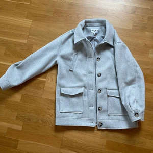 Grå Jacka med knappar i storlek 38, NAKD - Grå jacka med knappar från NAKD i storlek 38. Har två fickor. Köptes ny för 800kr. 