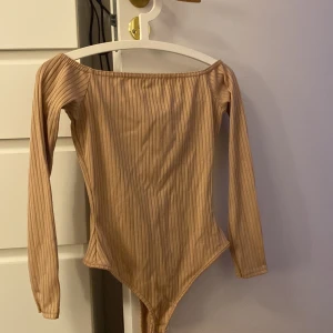 Beige body - En snygg beige body som är ribbad. Den är från nly one och har aldrig använt den. Offshoulder och 3 kvarts ärmad!