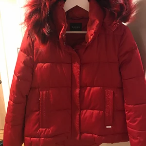 Vinterjacka Guess♥️ - Röd dunjacka av märket Guess, avtagbar huva och päls i svart/röd färg. Dragkedja och knappar framtill. Två sidofickor stängda med dragkedja. Har används enbart några gånger och är i väldigt bra skick.❣️(nypris 1399)