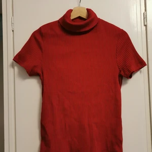 M/L röd topp t-shirt med hög krage, polo - Frakten är inkluderad i priset! Snygg topp / t-shirt från Cappucini med hög krage. Storlek L men passar de flesta beroende på hur man vill att den ska sitta. 🦊 Perfekt under en pullover! 