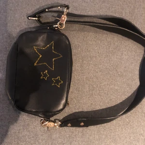 Svart väska med stjärnor  - Svart väska med stjärnor i guld, två fack på insidan ett på utsidan.