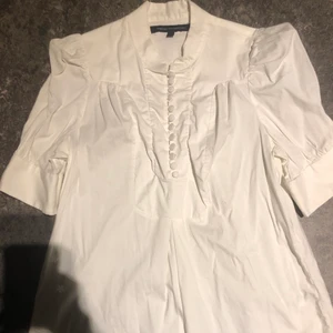 Vit blus French connection XS - Vit kortärmad blus med knappar till stängning. Är lång skulle även passa till en kort klänning men e verkligen mini i så fall.