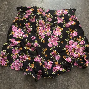 Blommig kjol shorts hög midja och korta i längd. Luftiga, tunna och blåsande material med två fickor fram till.