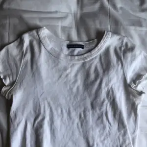 Kroppad vit t-shirt som är räfflad nertill från Brandy Melville.