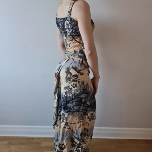 Somrigt set (topp+omlottkjol) - Superskönt somrigt set med topp & en lång omlottkjol (i sarongliknande modell) med knytning, fint tryck. Stl. M (toppen är strecthig & kjolen går att anpassa, så passar även S). Köparen står för frakten. Betalning via swish.