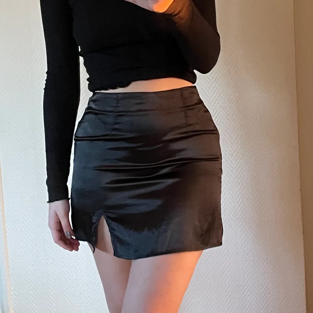 Trendig svart kjol i satin, säljer pga att den är för liten för mig🥺 Har dragkedja i sidan och en liten slits över vänster ben. Jag är 172 cm. Köparen står för frakten🤎. Kjolar.