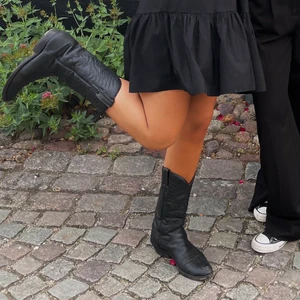 Svarta cowboy boots - Ett par svarta cowboy boots i läder. Storlek 40 men passar bra på mig som har storlek 39 då de är ganska smala i passformen. Sparsamt använda, i gott skick. De har lite slitningar på klacken vilket ses på bild tre men i övrigt är de finfina. Köptes för 400 kr.