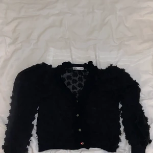 Svart kofta från zara - En tunn kofta med textur då det är tygbitar format som blommor som hänger från koftan.