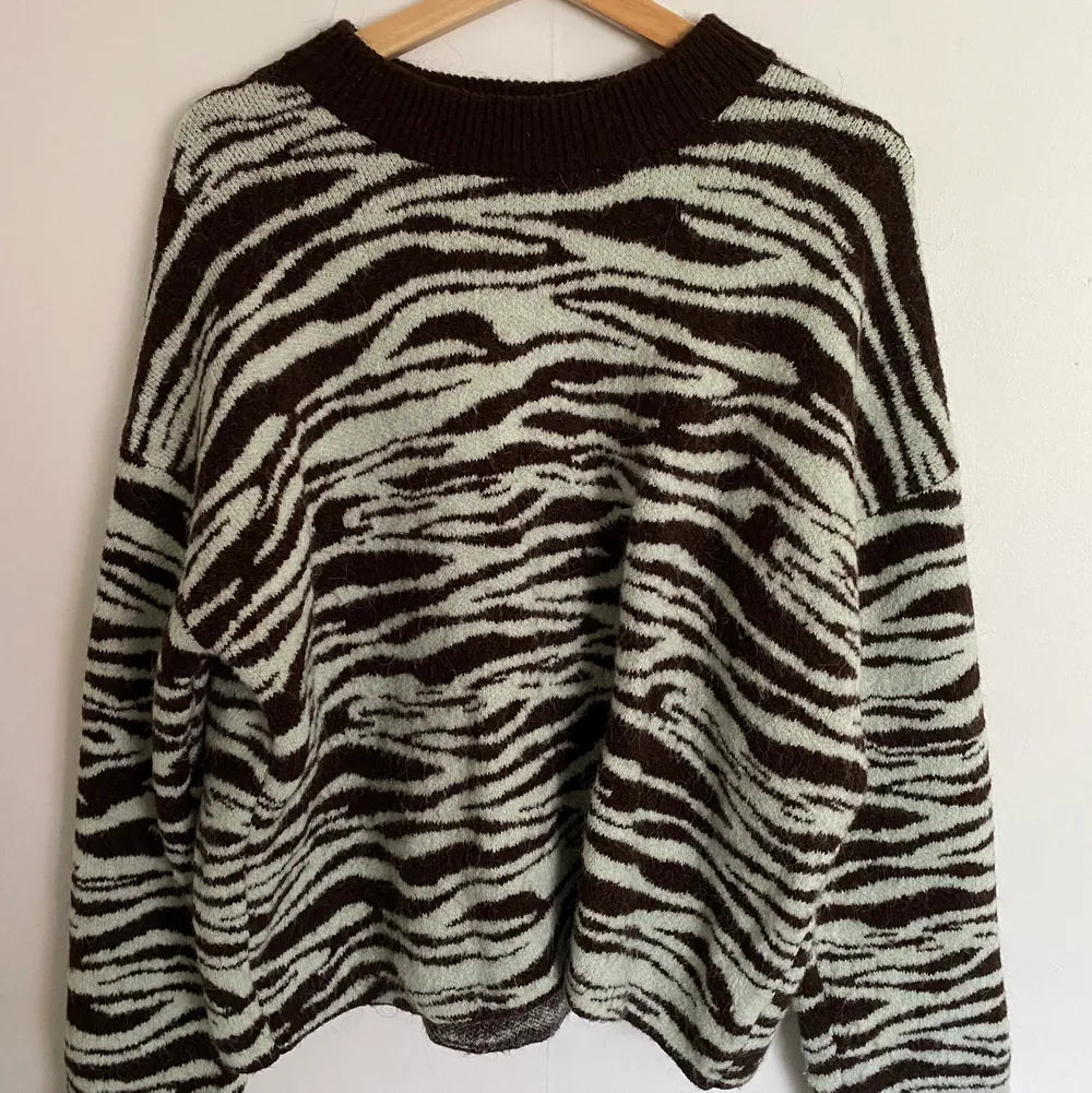 Super fin stickad tröja med zebra mönster från weekday. Mönstret är mörk brunt och mint färgat. Mått: arm 55 cm, längd 60 cm, bröst 60 cm.. Stickat.