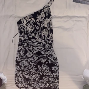 Mönstrad klänning - Säljer en ”one shoulder” klänning i blommigt mönster, aldrig använd, endast provad då den är för liten. Sitter tight. Nypris 559kr, köpt från Zara.