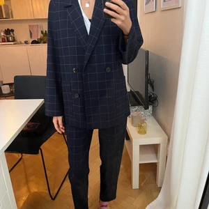 Rutigt kostymset  - Rutigt kostymset från monki, i mörkblått! Strl 34 i kavaj och strl 32 i byxorna! Saknas en knapp på kavajen. Men lätt att sy dit.