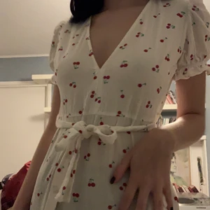 Klänning med körsbär  - Supersöt klänning med körsbär på. Skärp medföljer men går att ta av. Dragkedja på sidan 