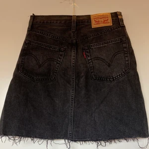 Levis jeanskjol - Superfin jeanskjol i svart med sliten tvätt. Fransar/klippt kant  längst ner. Storlek 24. Endast använd enstaka gånger, mycket fint skick! Köparen står för frakt (66kr spårbar) 