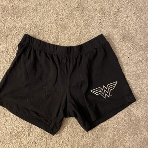 Mjukisshorts  - Ett par svarta pyjamasbyxor som jag ej vet vart de är ifrån med wonder women logga på väl använde men fortfarande i fint skick.
