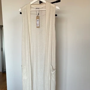 Lång kofta - En lång stickad kofta som når nästan hela vägen ner till marken på mig (162 cm). Aldrig använd och prislappen sitter fortfarande kvar. Supermjukt stickat tyg men tunn. Köpt på Vero Moda. Frakt tillkommer!