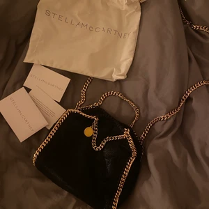 Stella McCartney falabella tiny - Intressekoll på min Stella McCartney falabella tiny svart/guld, nypris 6000kr. Guldet på runda loggan är lite bortskaft på baksidan (inget som syns när man bär väskan, kan skicka bild på de). I övrigt väldigt bra skick! Dustbag + äkthetsbevis medföljer!💕