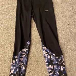 Träningsbyxor  - Ett par svarta träningsbyxor med lila blomor nere vid smalbenen. Använda ganska mycket men i bra skick. Köpta på stadium eller intersport kommer inte ihåg vilket av de