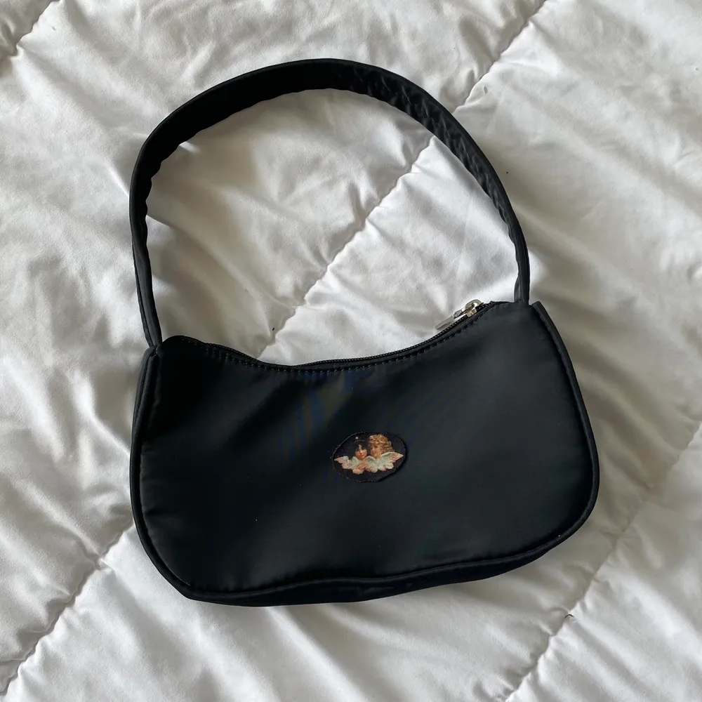 Jätte söt svart shoulder bag med två änglar. Ej använd. Frakt på 62 kr tillkommer 👼🏼🖤. Accessoarer.