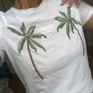 Vit t-shirt med palmer  - En riktig sommar t-shirt med 2 stora palmer på. Den kommer ifrån H&M och är i storlek M, storleken känns inte oversize och inte heller tight (är vanligtvis en storlek S/M). Palmerna är sydda på tröjan :)