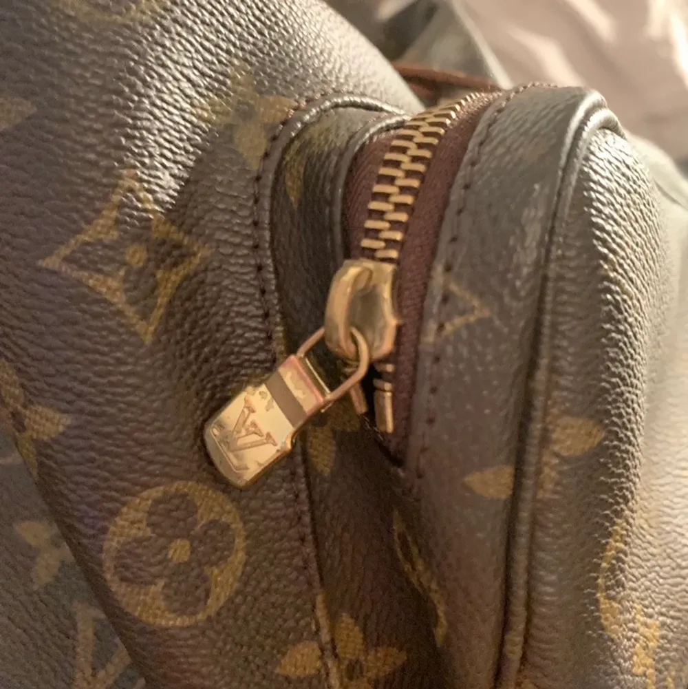 Brun monogramduk och Golden Brass-hårdvara.  Ljus patina med fläckar. Canvas i bra skick.  Den har ett utvändig ficka med blixtlås på framsidan.  Läder pull -sträng stängning med lock topp för säkerhet, en interiör med ficka med blixtlås även där.  Mycket rymlig och stilren Mått: 30 * 35 * 12cm Väskan är välanvänd.   Sömmen har släppt på baksida undersida. (se bild)Detta går att lämnas in till en bra skinn skräddare för 1000 kr.  Inköpt på herr Judith 2017   Datum Kod  : MI 0030  (March 2000 in . Väskor.