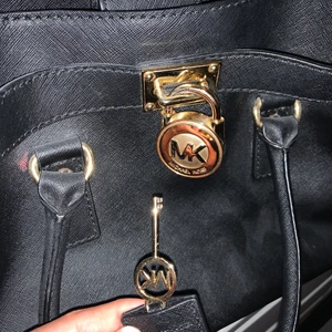 MICHAEL KORS HAMILTON - ALDRIG ANVÄNT VÄSKAN!! Skitsnygg Michael kors hamilton med lås. Den har en liten öppning där nyckeln gömmer sig, super diskret. Väskan kan bära på massor och är jätte elegant. Köptes för 4800kr men utropspriset är bara 1000kr!  OBS. VÄSKAN ÄR ÄKTA!!! Har kvar mk och nk påsen som ni kan se och den har en qr kod ni kan scanna där ni ser att den är 100% äkta.