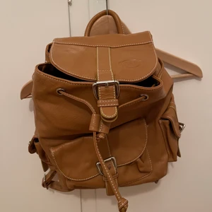 Ryggsäck i fuskläder - Ryggsäck med fina detaljer och många fack. Helt oanvänd. Vid post tillkommer frakt.