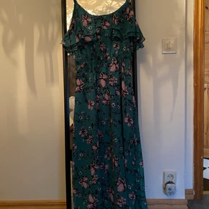 Sommarklänning från Ginatricot - En oanvänd grön klänning med rosa blommor på från Ginatricot i storlek 39.