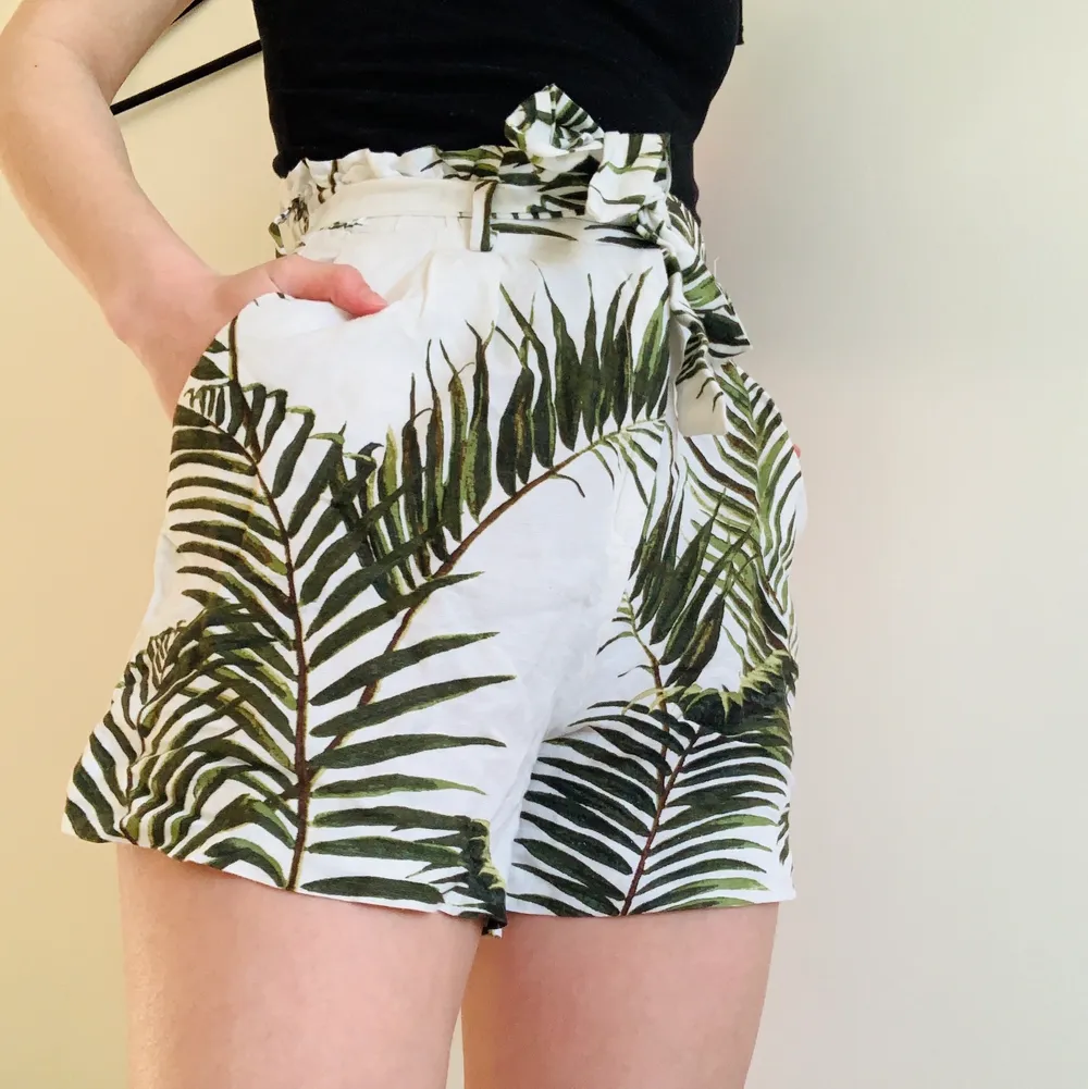Shorts med djungelmönster/plantor på. Loose fit, linne-blandning. Använd en eller två gånger så i riktigt bra skick. Knytband/bälte i midjan . Shorts.