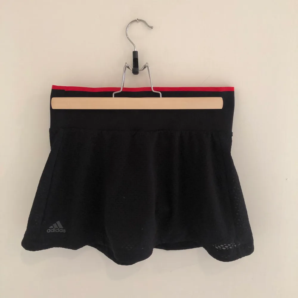 Tenniskjol med inbyggda shorts. Snygg röd detalj i linningen. Köparen står för frakt. . Kjolar.