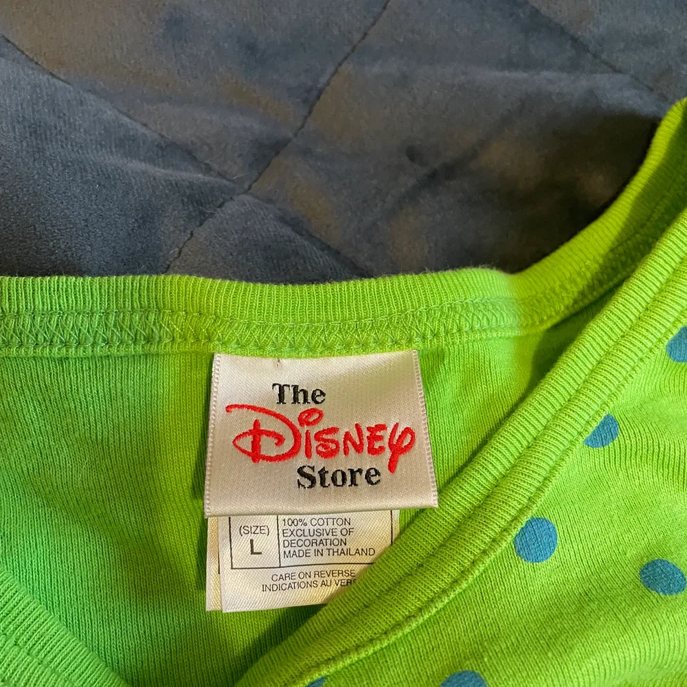 En grön arm-lös tröja med blå prickar. Cool icon på framsidan av Musse pigg. Cool att styla. Kommer från en Disney Store men jag köpte den second hand i Lund. . T-shirts.