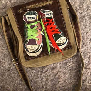 axelväska med skodetaljer - Jättefin väska med skodekorstion på framsidan, säljs pga kommer ej till använding. är i bra skick och har många bra fack