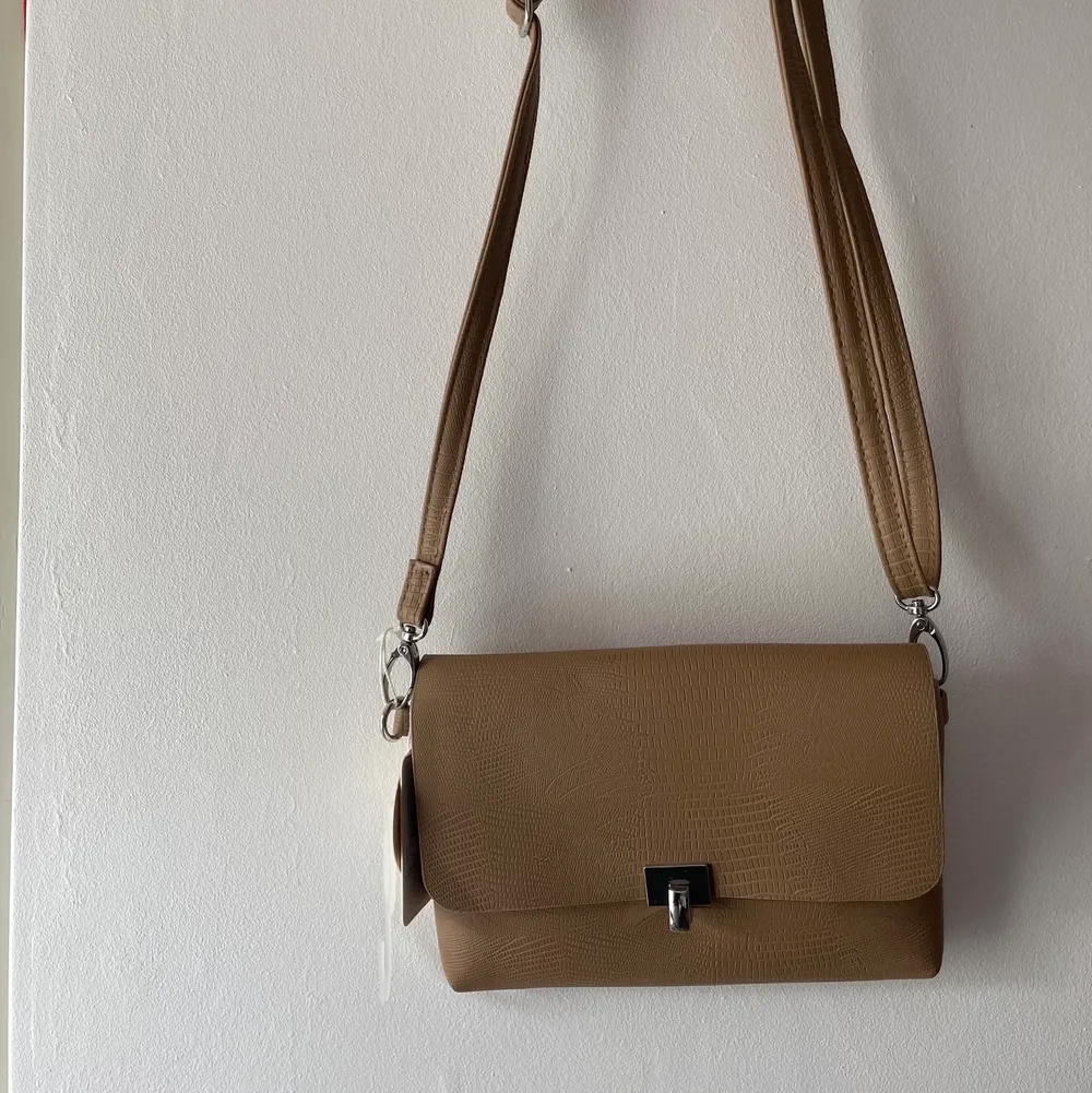 Snygg beige väska, aldrig använd, prislappen är kvar. Från Primark. Axelbandet är justerbart.. Accessoarer.