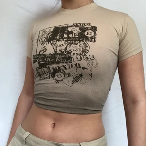 Beige Babytee - Unik beige babytee med coolt tryck på. Helt sprillans ny. Aldrig använd med lapp kvar. (104-110)  Uppskattas till storlek xs/s. Visas på en s och sitter bekvämt utan att dra åt någonstans. Köpare står för frakt. 