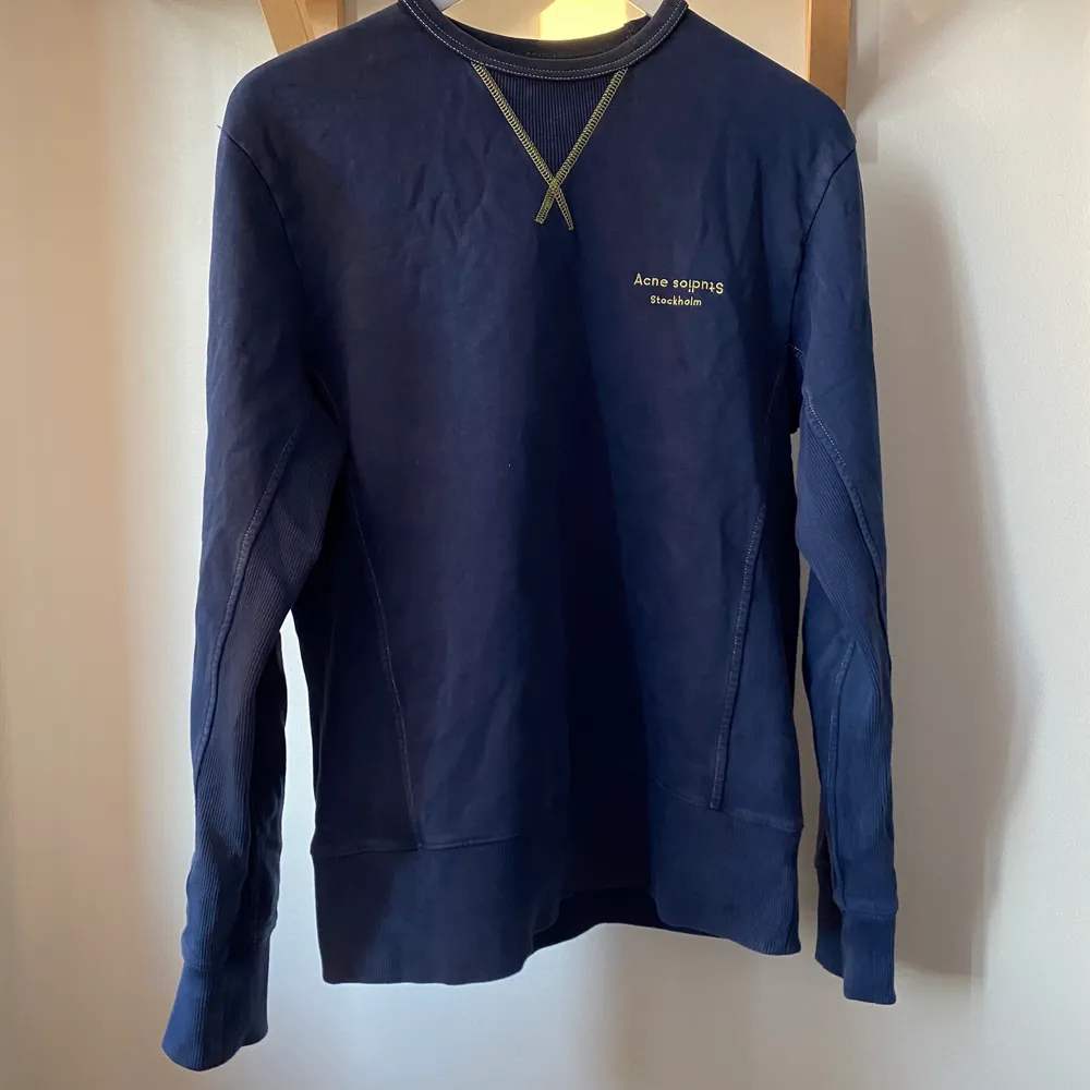 Säljer en blå tröja sweatshirt från Acne Studios med gröna detaljer. Tröjan är använd fåtal gånger och har inga som helst defekter eller liknande, förutom att taggen i nacken trillat av av sig självt (se bild 3) men den går lätt att sy på igen om man skulle vilja det. Storleken är XS men skulle säga att den sitter som en S. . Tröjor & Koftor.