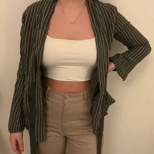 Grön/vitrandig blazer 38 - Grön- och vitrandig blazer från WERA Stockholm, storlek 38, för referens är jag vanligtvis S/M (36/38) i toppar. Snöre att knyta antingen framtill eller baktill. Använd en gång och är i nyskick, lite skrynklig bara men det går att stryka. 50% CUPRO, 40% VISKOS, 10% POLYESTER, tunt material. Nypris ca 600kr, säljer för 50kr (+ frakt)