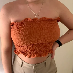 Ribbad bandeautopp M - Ribbad bandeautopp med volanger från Nelly.com, rostfärgad, jag är vanligtvis M/S i toppar och har bhstorlek 75D/E för referens. Den är väldigt stretchig och passar nog mellan S-L beroende på önskad passform. Säljs inte längre, är i bra skick. Säljer för 80kr inklusive frakt, vid köp tillsammans med samma tröja i svart - 130kr inklusive frakt!