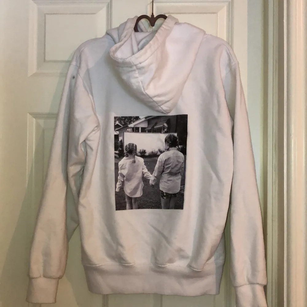 En vit hoodie med bild på ryggen, dock har den en lite fläck på vänster axel. Hoodies.