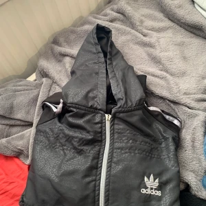 Adidas tröja - Nyskick, dragkedjan funkar men den man håller i gick sönder men det kan man byta, annars fel fritt plagg. Kan skickas men då står köparen för frakt, finns annars i Falköping. (Kan skickas med spårbar eller eget paket)