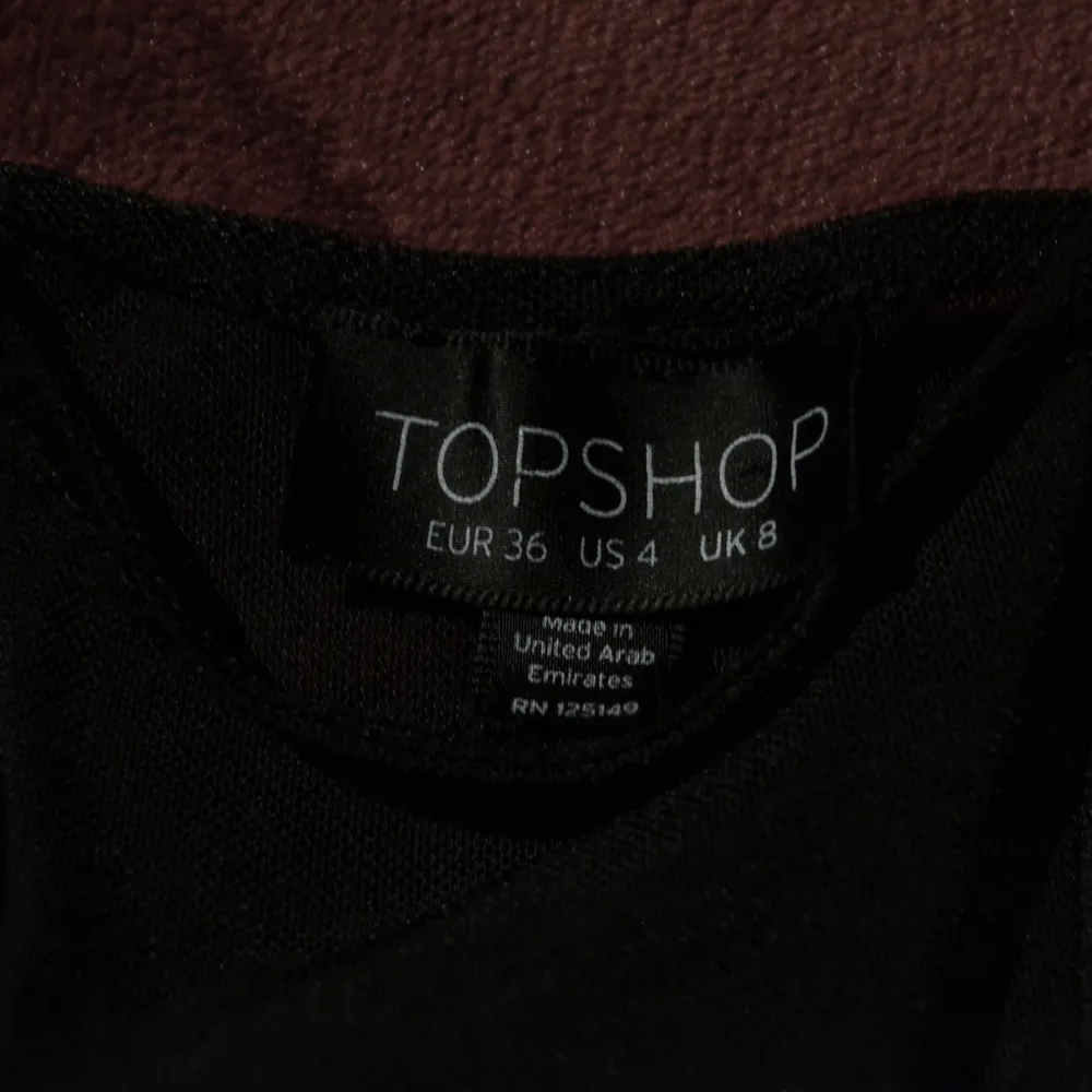Kort svart klänning från Topshop, med genomskinlig rand där fram och genomskinlig rygg. Har lite vaddning i axlarna och en fin form! Köpare betalar frakt, betalning görs via Swish. Klänningar.