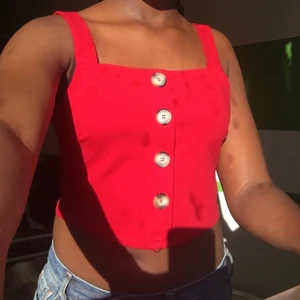 En fin röd topp i stl.M - En jättefin röd topp med knappar över bröstet. Den är aldrig använd. Fläckarna kommer från mitt fläckiga fönstret så tröjan är ren. Knapparna är endast sydda på tröjan så de kan inte knäppas upp.