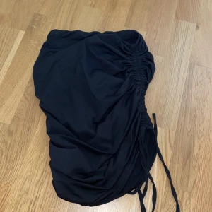 Kjol  - Tight svart kjol med snörning i sidan så man kan knyta den så den blir kortare. Sitter bra och formar baken snyggt!